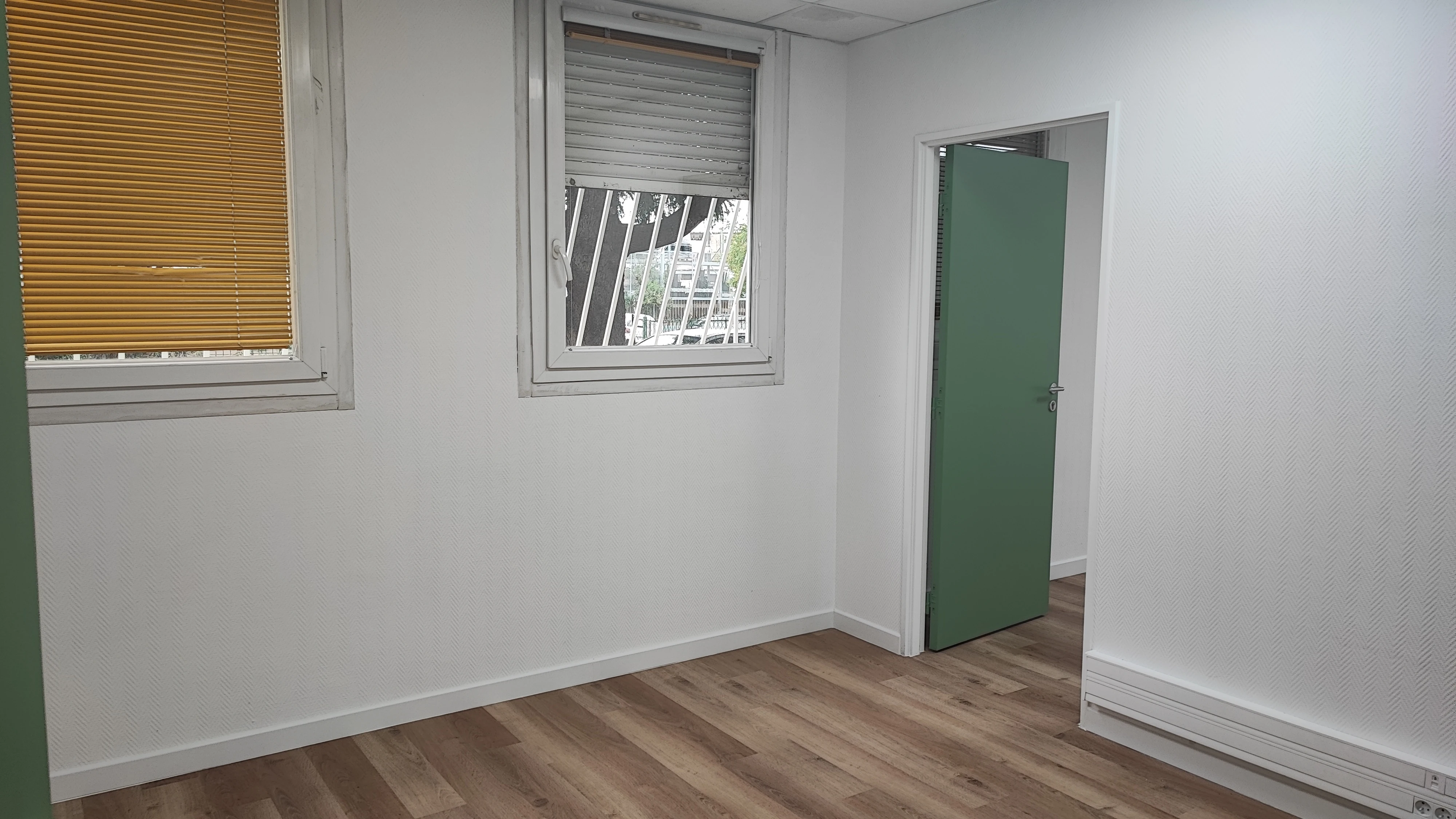 Bureau rénové lumineux avec sol effet bois et porte verte — ADMR Salon-de-Provence