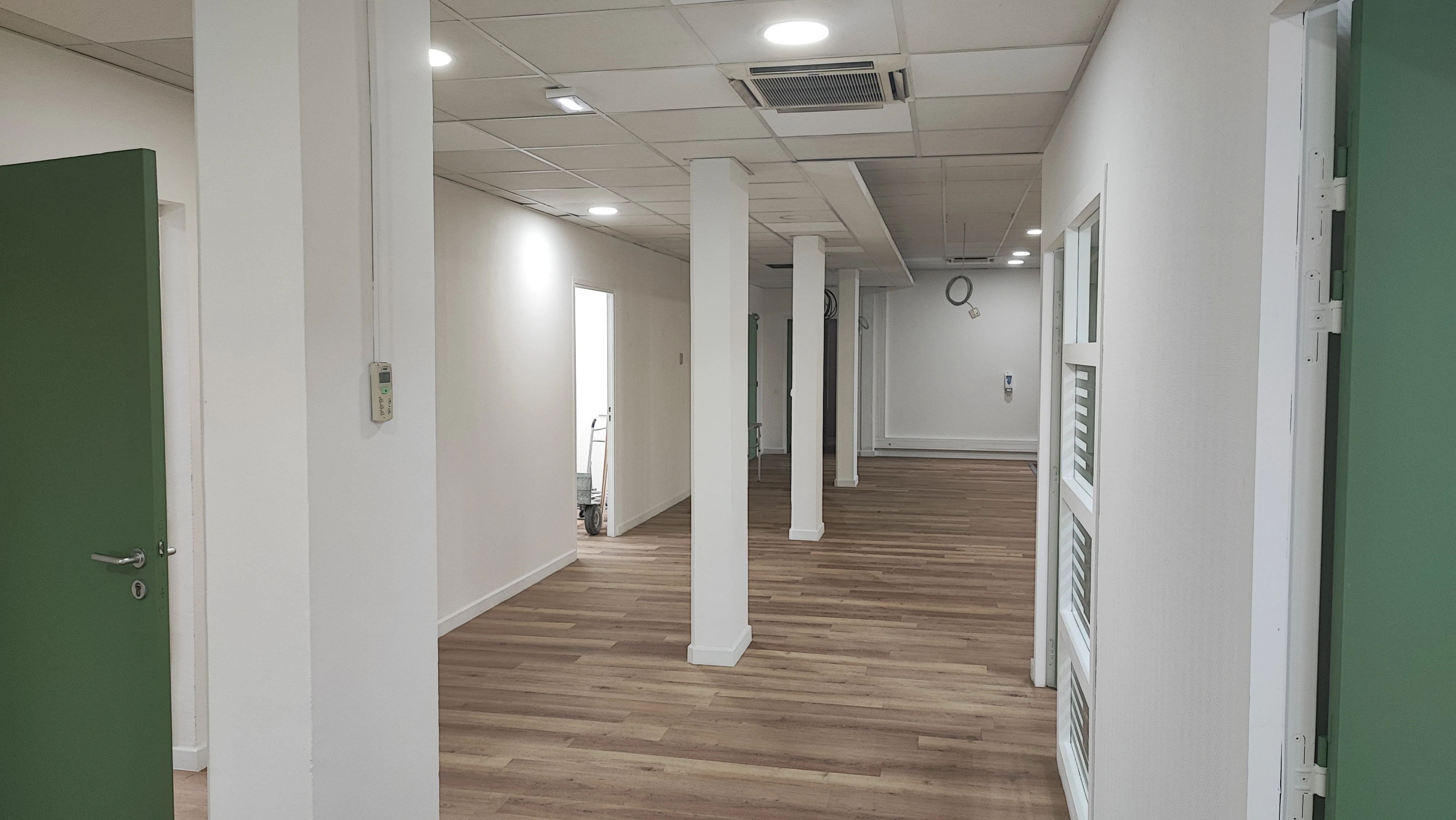 Couloir de bureaux rénové avec portes vertes et faux plafond neuf — ADMR Salon-de-Provence