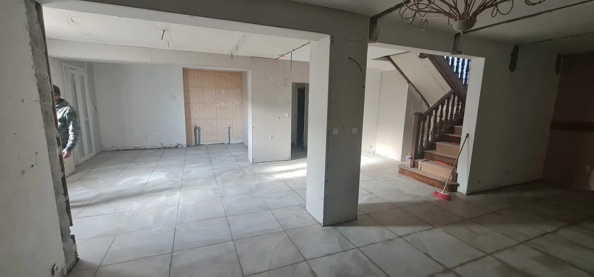 Pose de carrelage neuf grand format dans le séjour ouvert avec escalier en bois