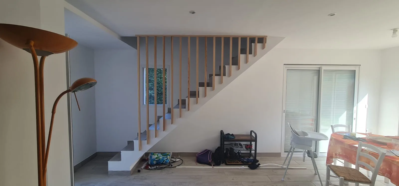 Séjour rénové avec escalier en béton, garde-corps à claire-voie bois et baie vitrée coulissante
