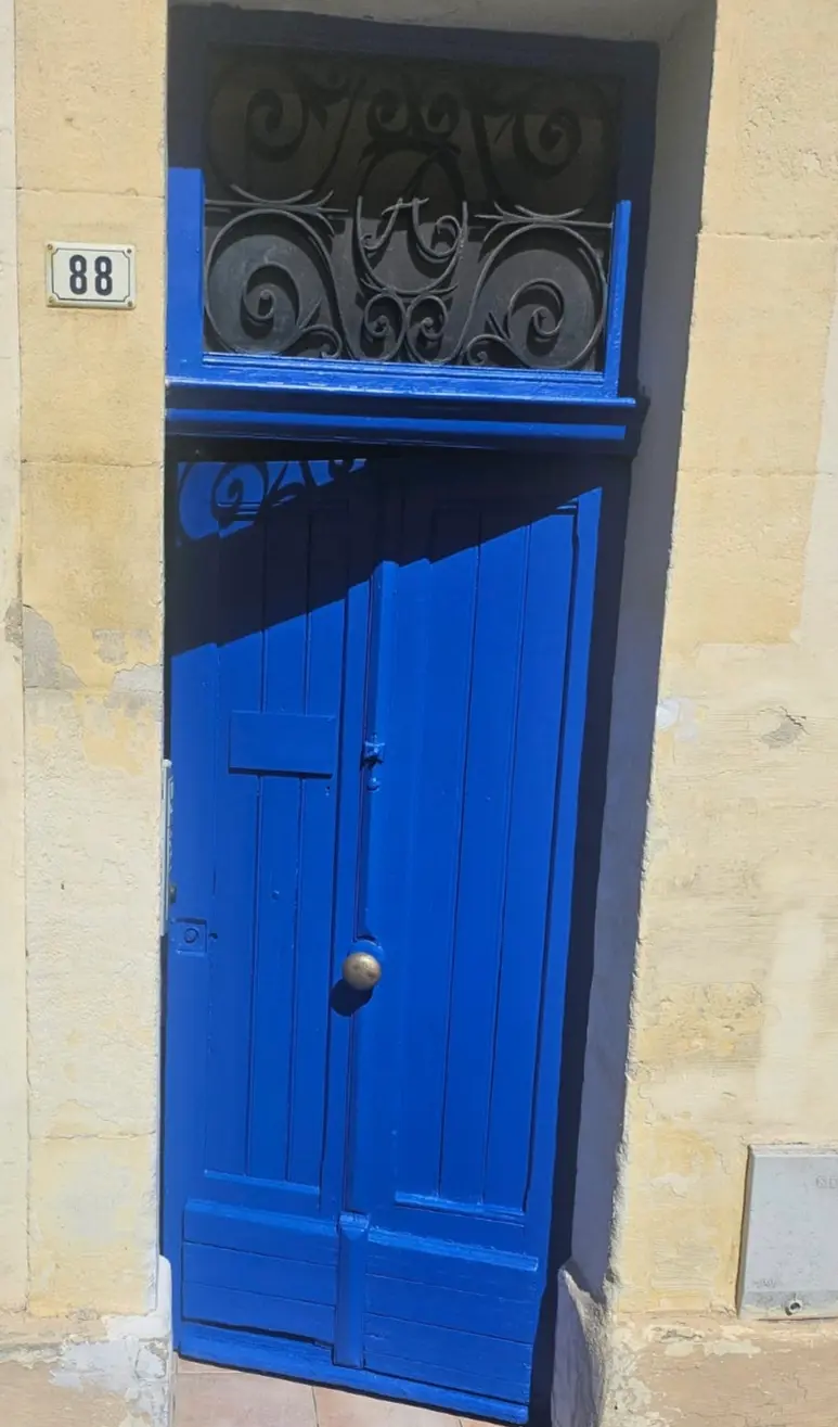 Porte en bois restaurée avec imposte en fer forgé
