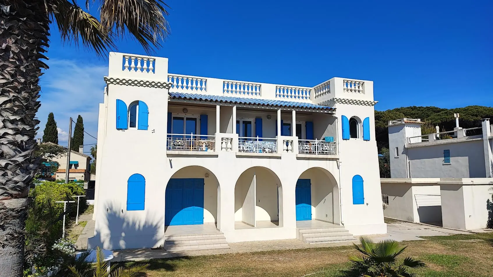 Vue d'ensemble de la villa château rénovée à Saint-Cyr-sur-Mer, façade blanche et bleue depuis le jardin