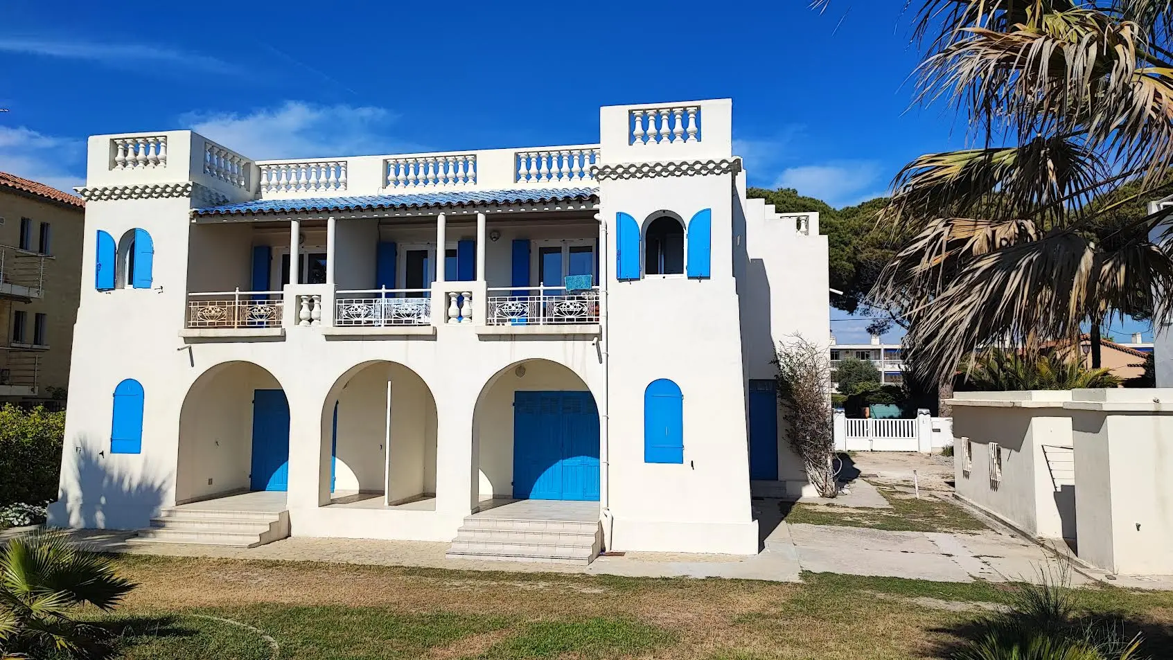 Façade rénovée de la villa vue de côté, tourelles blanches et volets bleus à Saint-Cyr-sur-Mer