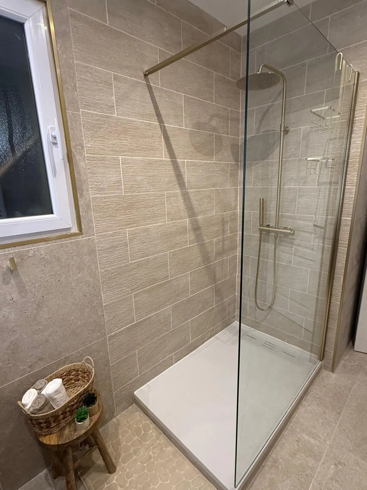 Installation de la douche à l'italienne avec robinetterie dorée et paroi vitrée