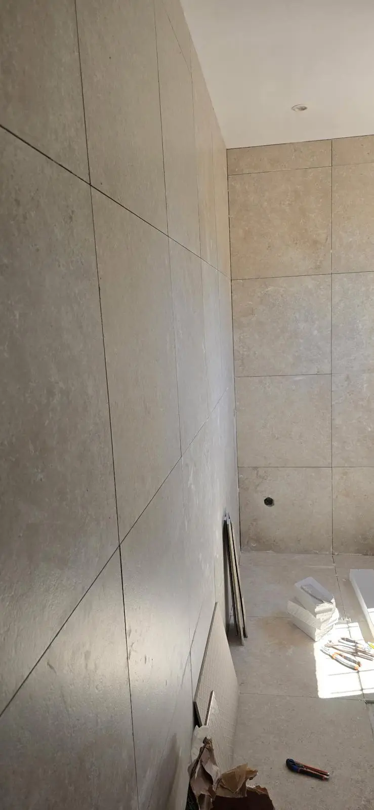 Pose du carrelage grand format sur les murs et le sol de la salle de bain
