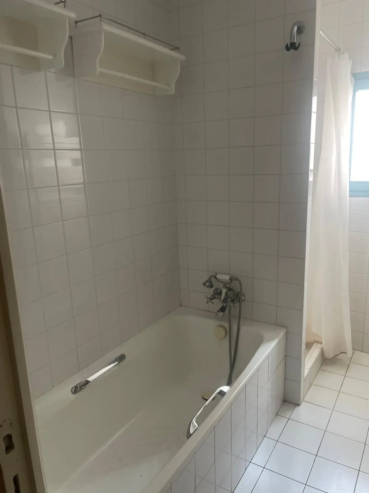 Avant rénovation — baignoire encastrée carrelée blanc avec robinetterie rétro chromée